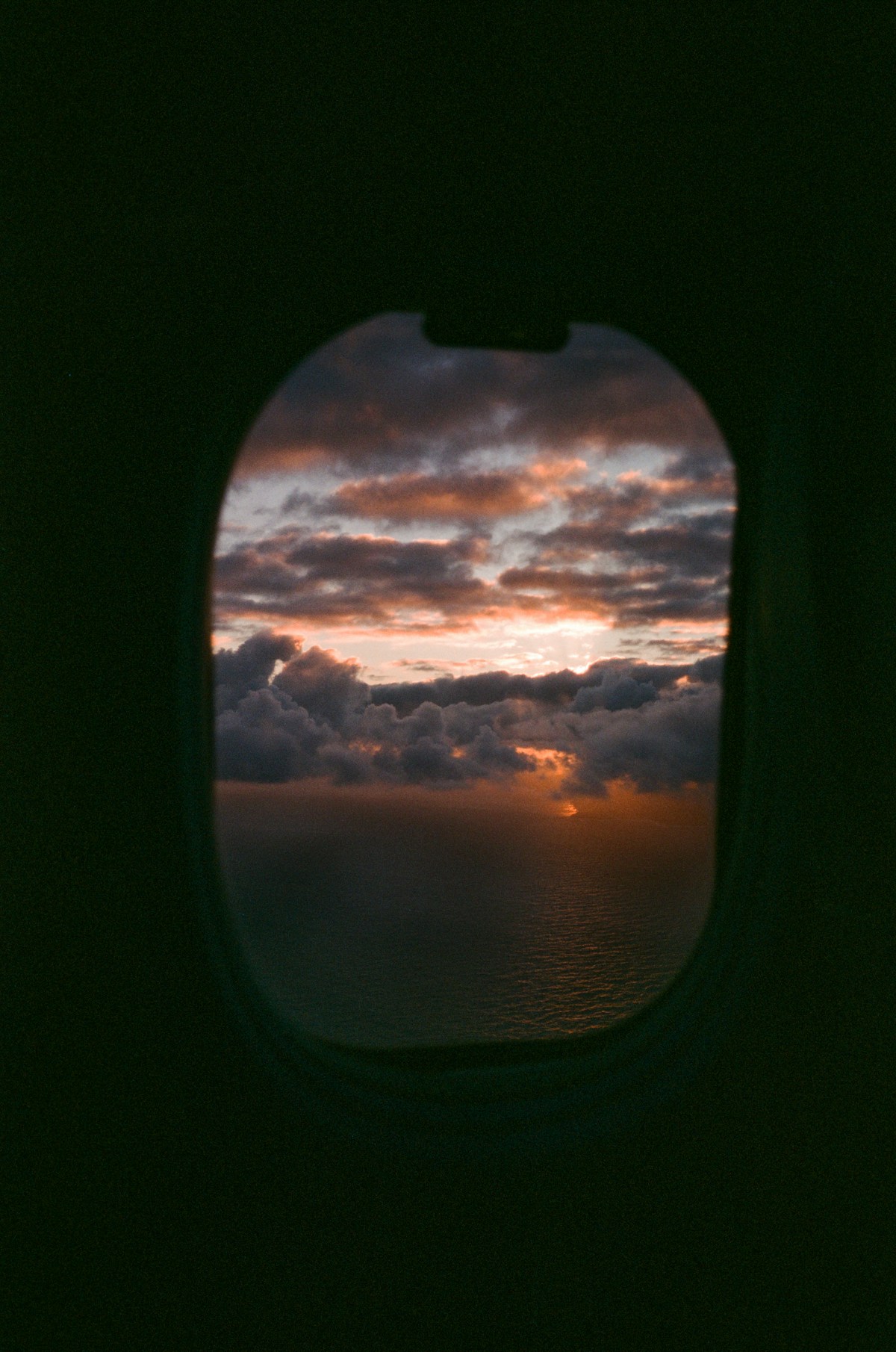 Sonnenuntergang und Wolken durch ein Flugzeugfenster